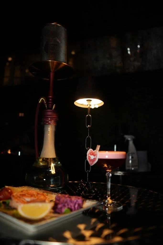 Hookah, cocktail and salmon under a table lamp