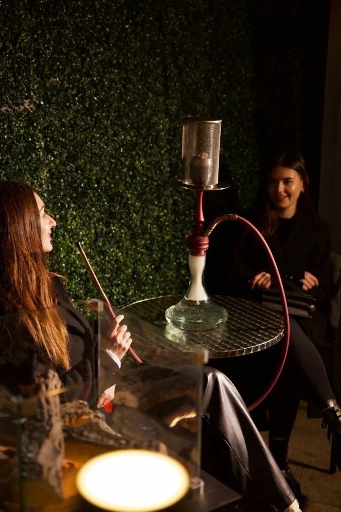 Two guests sharing shisha by the living wall